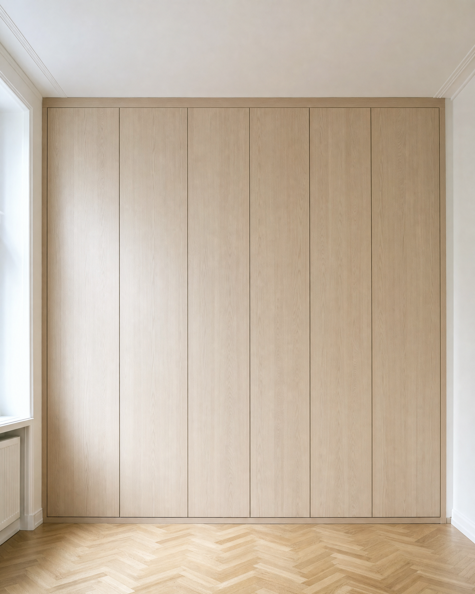 Raumhoher maßgefertigter Einbauschrank aus hellem Holz in einer Wiener Altbauwohnung mit Parkettboden